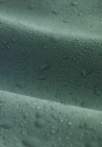 Suprafață de verde închis cu picături de apă; textură netedă, ușor reflectorizantă, arătând dimensiuni variate ale picăturilor pe un fundal mat.