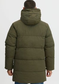 Chaqueta de plumas verde oliva con capucha, presenta secciones acolchadas y un corte recto. Textura suave, mangas largas y sin herrajes visibles.