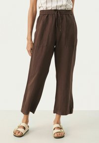 Bruna linbyxor med en lös passform, elastiskt midjeband och två framfickor. Matchas med beige sandaler med spänne.