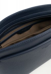 Interno di una borsa in pelle textured blu navy, con una fodera liscia marrone e un compartimento con zip per un'archiviazione sicura.