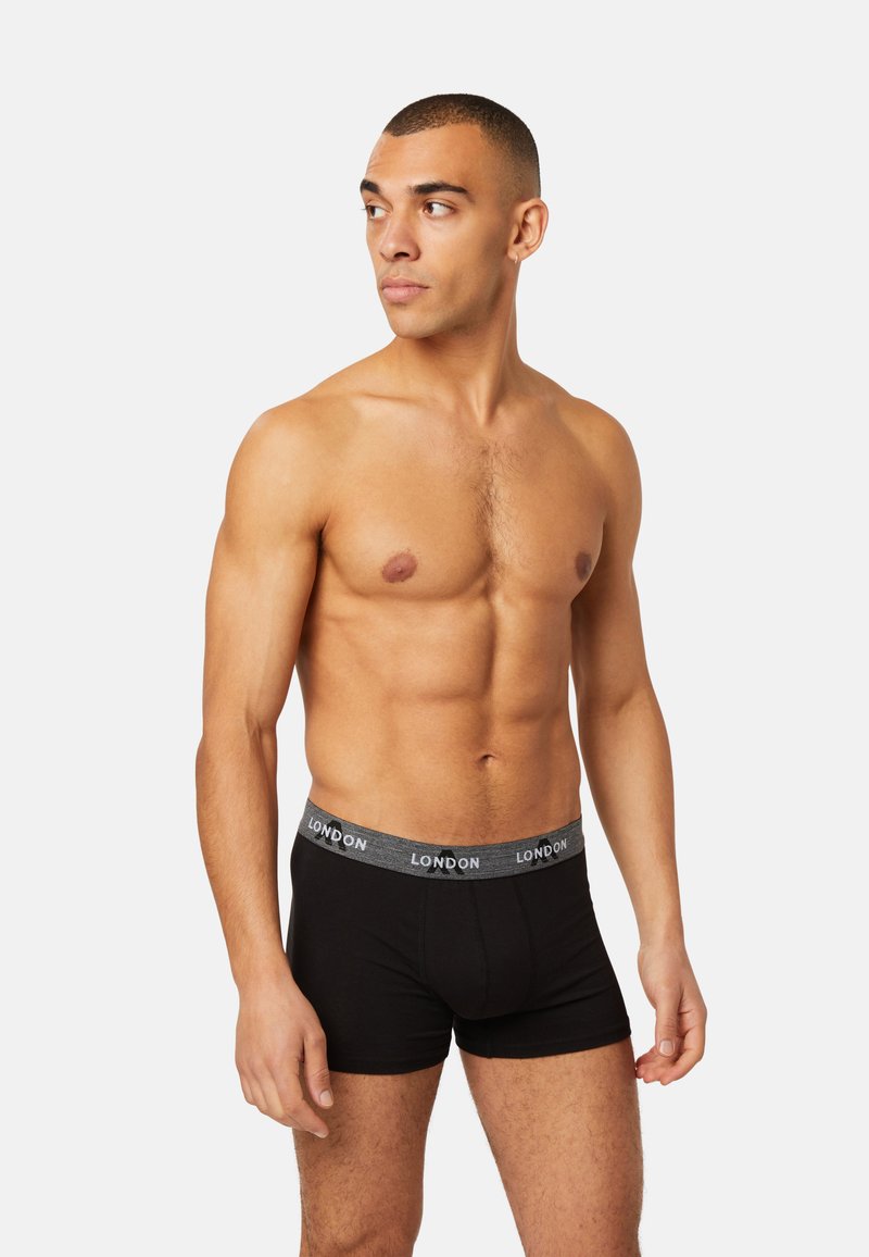 Black cotton boxer shorts with a grey waistband featuring "LONDON" in white. The model is shirtless, showing a muscular build.