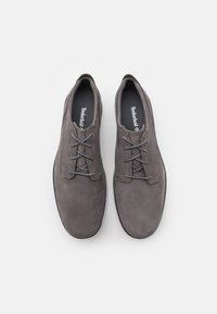 Zapatos de ante gris con un acabado suave, punta redonda, cinco ojetes y cordones grises. Las plantillas negras presentan el logo de Timberland.