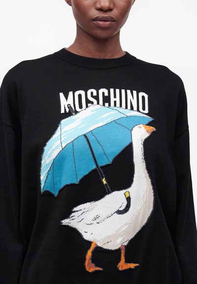 Άτομο που φοράει μαύρο πουλόβερ Moschino με λευκή χήνα που κρατάει μπλε ομπρέλα στο μπροστινό μέρος