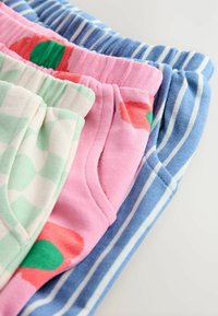 Tre paia di pantaloni corti esposti: verde menta a quadri, rosa con fiori rossi e verdi e blu a righe. Materiale in cotone e vita elastica.
