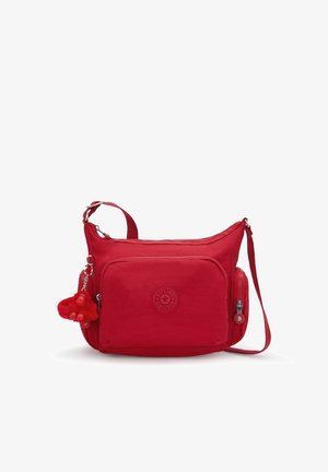 Sac bandoulière rouge en tissu durable, doté d'un compartiment principal zippé, d'une poche avant et d'un porte-clés singe en peluche.
