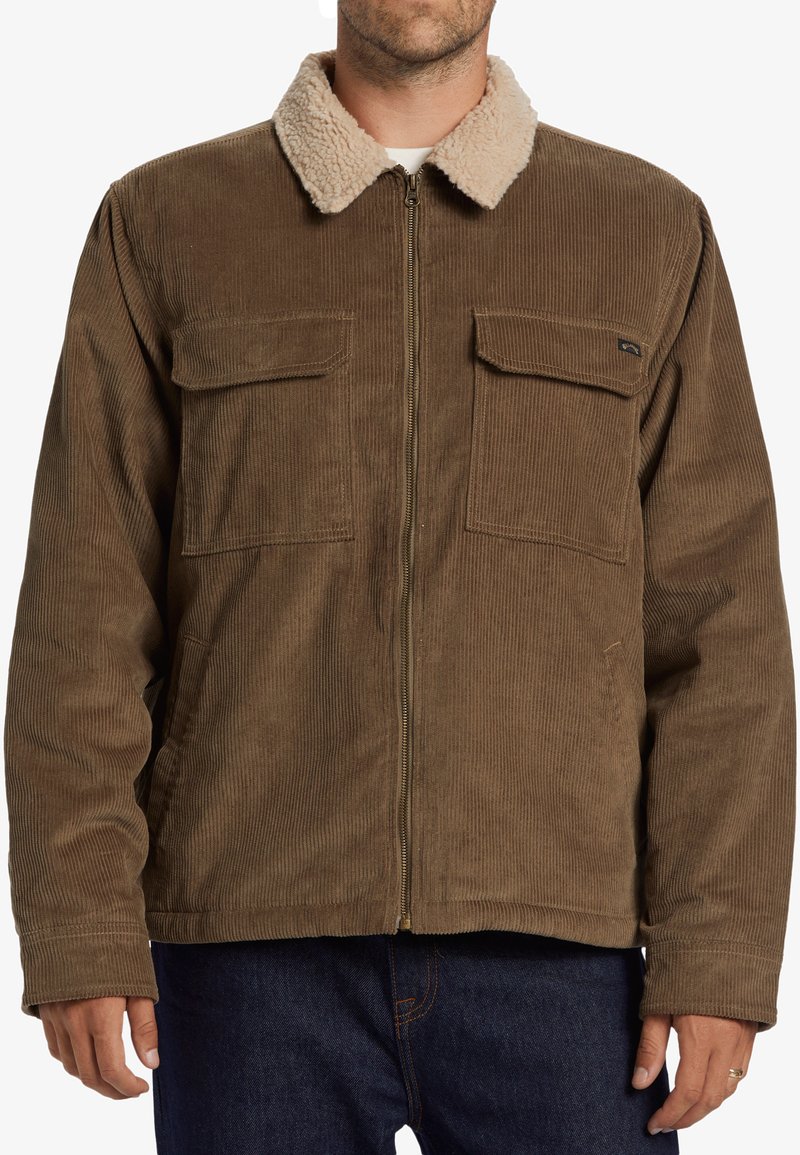 Chaqueta de pana marrón con un cuello de borrego beige, dos bolsillos en el pecho y un cierre frontal de cremallera. Tiene un corte relajado y una tela texturizada.