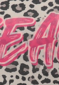 Leopard print fabric featuring bold, pink text that reads "EACH" with a glossy finish. The background is a light beige color.