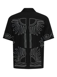 Chemise noire à manches courtes avec des motifs abstraits blancs de soleil et de lignes tourbillonnantes dans le dos et sur les manches, avec un col droit.