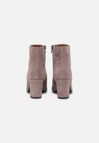 Botas de tobillo de ante gris con tacón cuadrado, que cuentan con un cierre lateral, textura suave y detalles de costura mínimos.