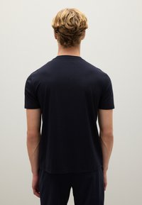 Camiseta de manga corta de color azul marino, hecha de una tela suave, con un escote redondo y un dobladillo recto, vista desde la parte de atrás.