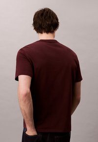 Camiseta de algodón burdeos de manga corta y cuello redondo, con una textura suave y un corte relajado para un uso casual.