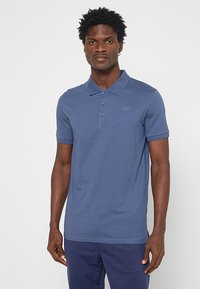 Koszulka polo z krótkim rękawem w ciemnoniebieskim kolorze, wykonana z bawełny. Posiada kołnierzyk, trzy guziki oraz subtelne logo na piersiach. Gładka texture.