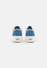 Baskets en toile bleue avec des détails en dentelle blanche, semelle plateforme et logo Vans sur le talon. Texture lisse avec un design à bout rond.