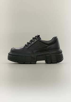 Crni kožni platform čevlji s debelim teksturiranim potplatom, vezicama sprijeda i obloženim ovratnikom, prikazani na neutralnoj pozadini.