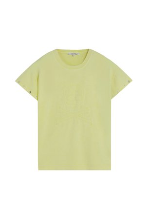 Camiseta corta de manga corta de color amarillo claro con un diseño sutil en relieve de una calavera y tibias cruzadas en la parte delantera y pequeñas tachuelas metálicas en las mangas.