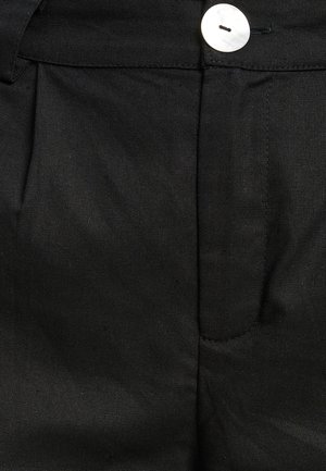 Black fabric trousers with a smooth texture, featuring a streamlined design, front crease, and a white button closure.