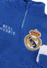 Pullover in pile blu con colletto a mezza zip, caratterizzato dal testo "REAL MADRID" e dal logo del club ricamato con corona, texture morbida.