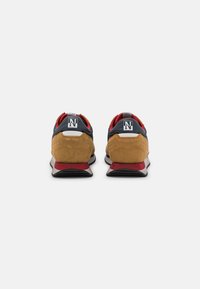 Sneakers con una toma in suede beige, accenti blu navy e una suola rossa e nera. Include un dettaglio del logo e un colletto imbottito per il comfort.