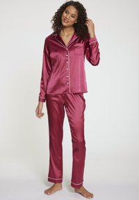 Bordeaux satijnen pyjamakostuum met een knoopsluiting aan de bovenkant, voorzien van een zak en afgewerkte accenten, gecombineerd met bijpassende broeken, gladde textuur, lichtgewicht ontwerp.