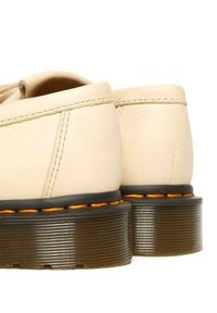 Scarpe in pelle beige dalla forma arrotondata, con una suola nera testurizzata e cuciture arancioni lungo il bordo per un contrasto.