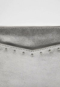 Silverfärgad läderkuvertväska med en texturerad yta, som har nitar längs kanten och en triangelmönster högst upp.