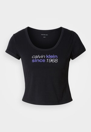 Black cotton t-shirt with a fitted design, scoop neckline, short sleeves, and white and purple text reading "calvin klein since 1968."
