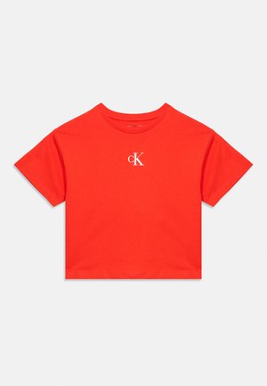 Rød cropped T-shirt med korte ærmer, hvidt "cK" logo centreret på brystet og rund halsudskæring.