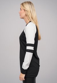 Haut à manches longues noir et gris avec des manches contrastantes et des accents rayés. Tissu doux, coupe décontractée et encolure ronde.
