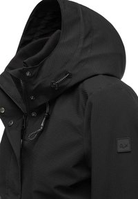 Veste isolée noire avec une surface texturée, capuche ajustable avec cordon de serrage, boutons-pression et logo en patch sur la manche.