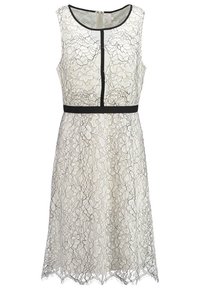 Robe en dentelle couleur crème avec des motifs floraux, bordure noire et taille cintrée. Sans manches avec un col rond et un ourlet festonné.