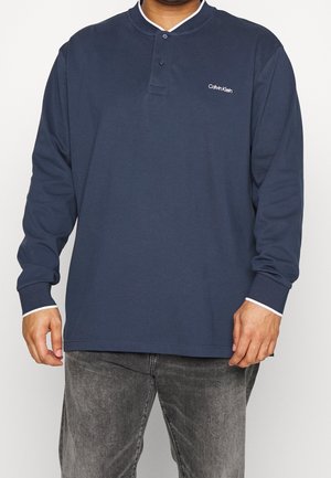 Marineblå långärmad polo med krage, tvåknappsknäppning, vita detaljer på kragen och ärmsluten, med Calvin Klein-logotyp på bröstet.