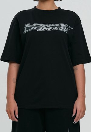 Black oversized t-shirt made of cotton with short sleeves featuring a silver graphic text design "LOW LIGHTS" across the chest.