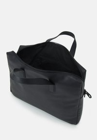 Black leather bag with a textured surface, top zipper closure, inner pocket, and short handle for easy carrying.