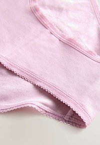 Roze katoenen ondergoed met golvende randen en een gladde textuur. Het ontwerp omvat een subtiele glans en een zakje in de tailleband.