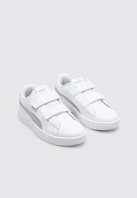 Sneakers bianchi con una tomaia in sintetico liscia, suola piatta e due strap in Velcro. Presentano un accento argentato sul lato e un collo imbottito.