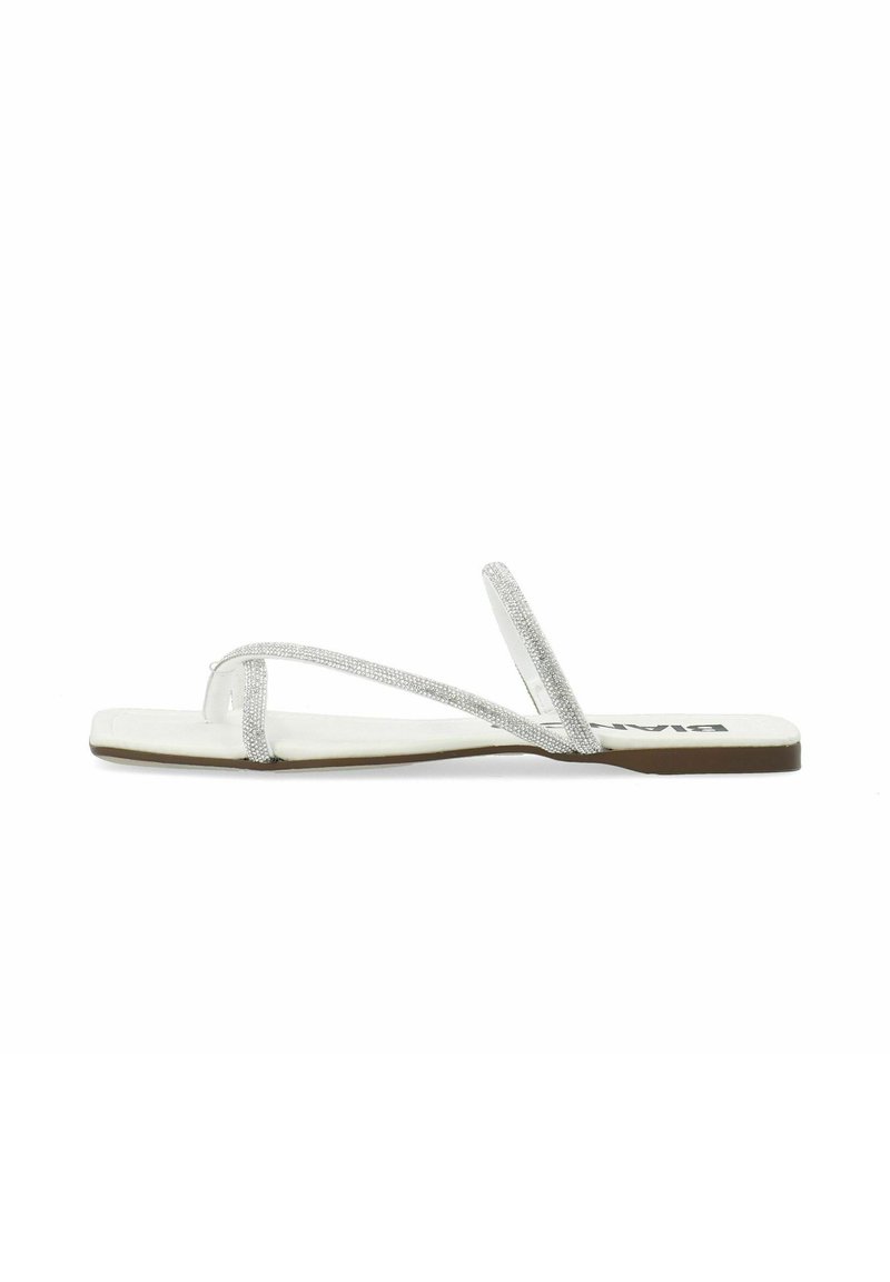 Tongs argent à paillettes avec fines brides, semelle plate et semelle intérieure blanche. Caractéristiques d'un design minimaliste et d'une texture lisse.