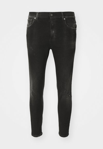 Jeans skinny neri in denim, con una finitura sbiadita e dettagli strappati sul davanti. Vita standard con passanti per cintura e tasche.