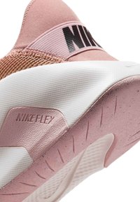 Sneakers Nike Flex s měkkým růžovým textilním svrškem, texturovanými detaily, černým brandingem a bílou gumovou podešví s dezénem.