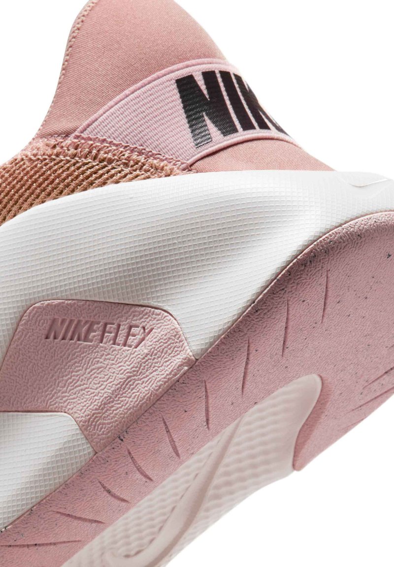 Nike Flex sneaker featuring a soft pink fabric upper, textured accents, black branding, and a white rubber sole with tread patterns.
