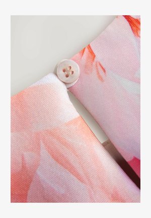 Textiel met een lichtroze stof met een bloemmotief en een ronde, gladde knoop op het kruispunt, met lichtbruine stiksels.