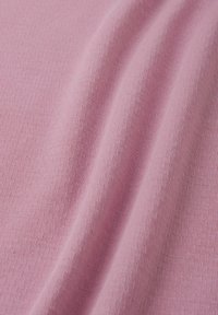 Dzianina w delikatnym różowym kolorze, charakteryzująca się gładką teksturą i subtelną elastycznością oraz drobnym prążkowaniem, prezentująca lekkie wykończenie.