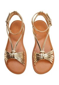 Zlaté metalické sandály s T-páskem, zdobené mašlí a texturovanou hnědou podrážkou. Nastavitelná spona kolem kotníku.