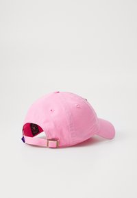 Rosa bomull baseballkeps med justerbar rem, böjd skärm och tygdetaljer på baksidan. Diskreta sömnadsaccenter på kronan.