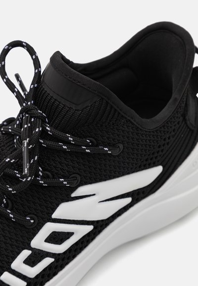 Black athletic shoe with a breathable knit upper, contrasting white accents, textured lace area, and a cushioned midsole.
