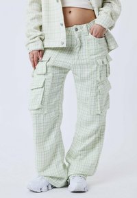 Groene en witte geblokte cargo pants met meerdere zakken, relaxte pasvorm en een gestructureerde stof. Gepaard met witte sneakers.