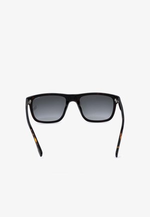 Lunettes de soleil rectangulaires noires avec des verres foncés dégradés et des branches à motif écaille sur fond blanc.