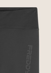 Leggings atletici neri caratterizzati da una vita alta, una texture liscia e una stampa verticale del logo grigio sul lato sinistro.