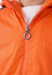 Giacca con cerniera arancione realizzata in materiale liscio e leggero. Presenta una zip con tiretto argentato e una fodera interna bianca.