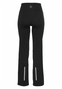 Schwarze Trainingshose mit hohem Taillenbund, versehen mit reflektierenden Streifen am Knöchel. Hergestellt aus dehnbarem Material für Komfort und Bewegungsfreiheit.