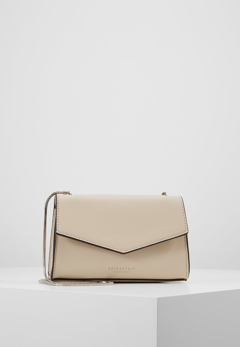 Borsa a tracolla in pelle beige con finitura testurizzata, chiusura a patta, bordi neri e tracolla a catena argentata. Logo impresso sul davanti.